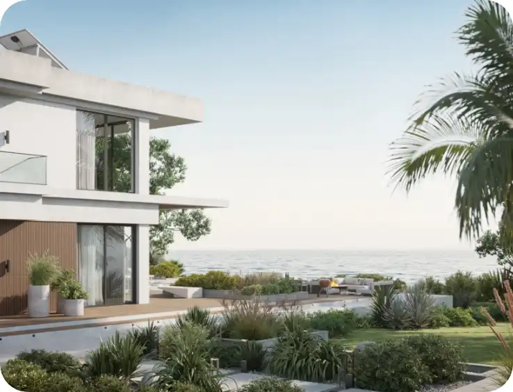 Modern two-storey white residential home with large glass windows and outdoor terrace, surrounded by tropical landscaping including palm trees and garden beds, with scenic views in the background